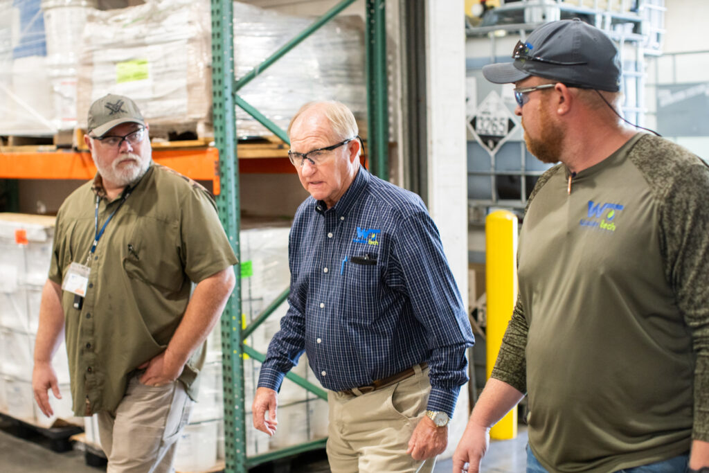 Three Water Tech employees with safety glasses on walk through a warehouse.