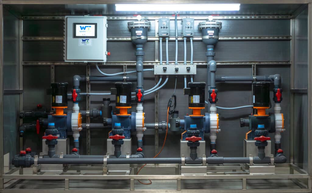 A system of gray, orange, and black pumps and pipes with a Water Tech sticker on the control box.