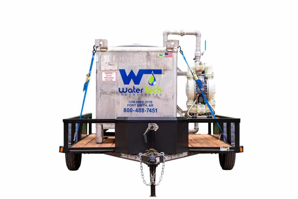 An ethanol tank on a trailer. The ethanol tank is scuffed and has caution signs on it. The Water Tech Incorporated logo is on the side in blue and green letters.
